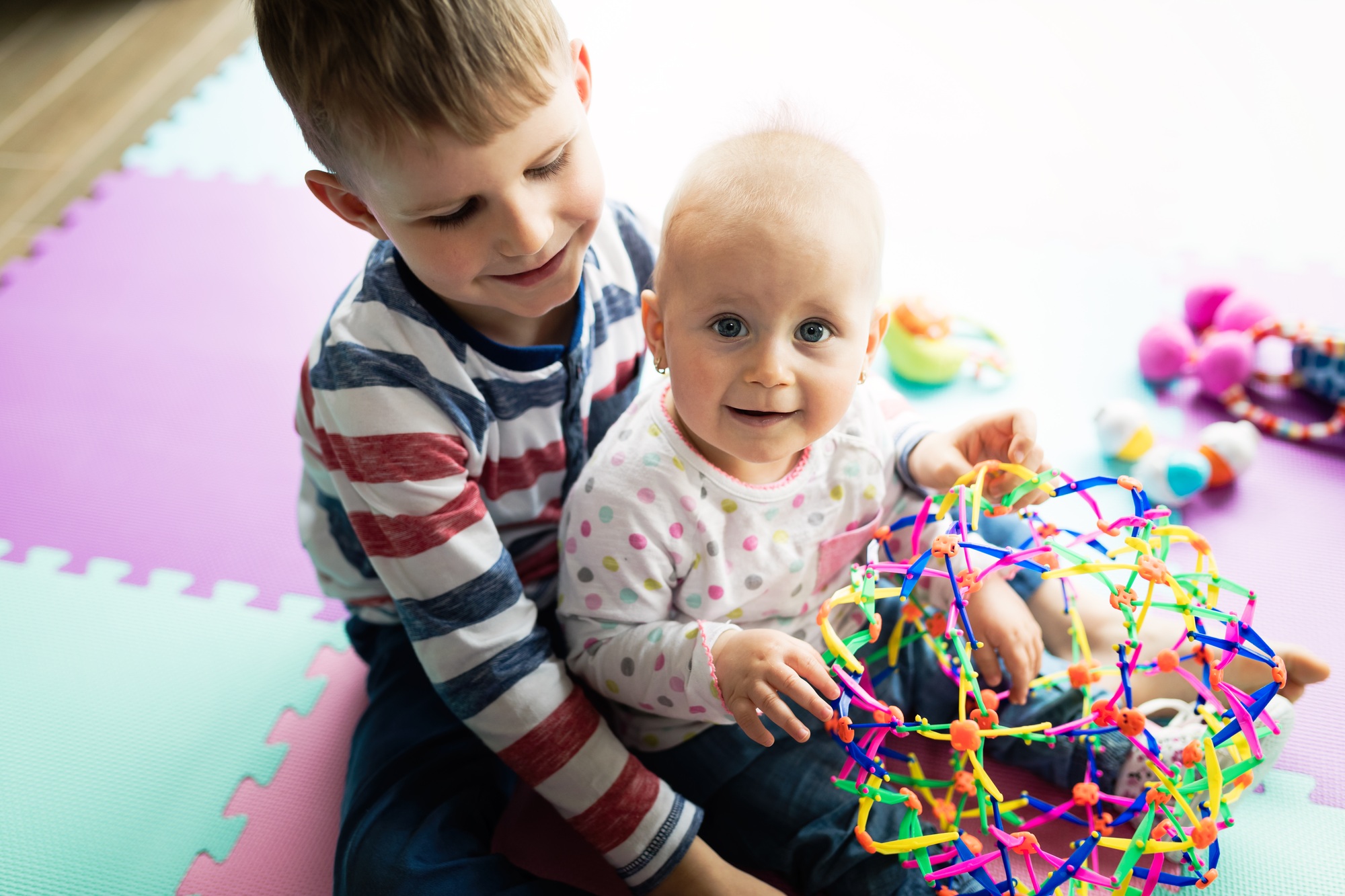 Cute little children playing while sitting on carpet